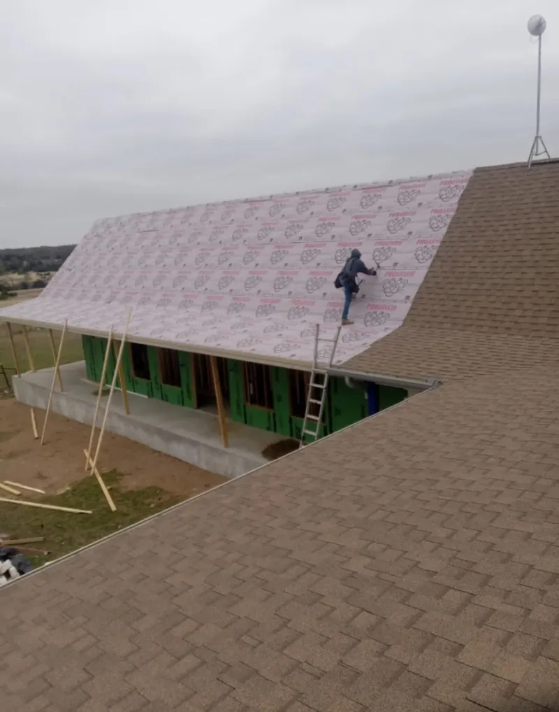 Worker preparing underlayment for a metal roof installation in West University Place